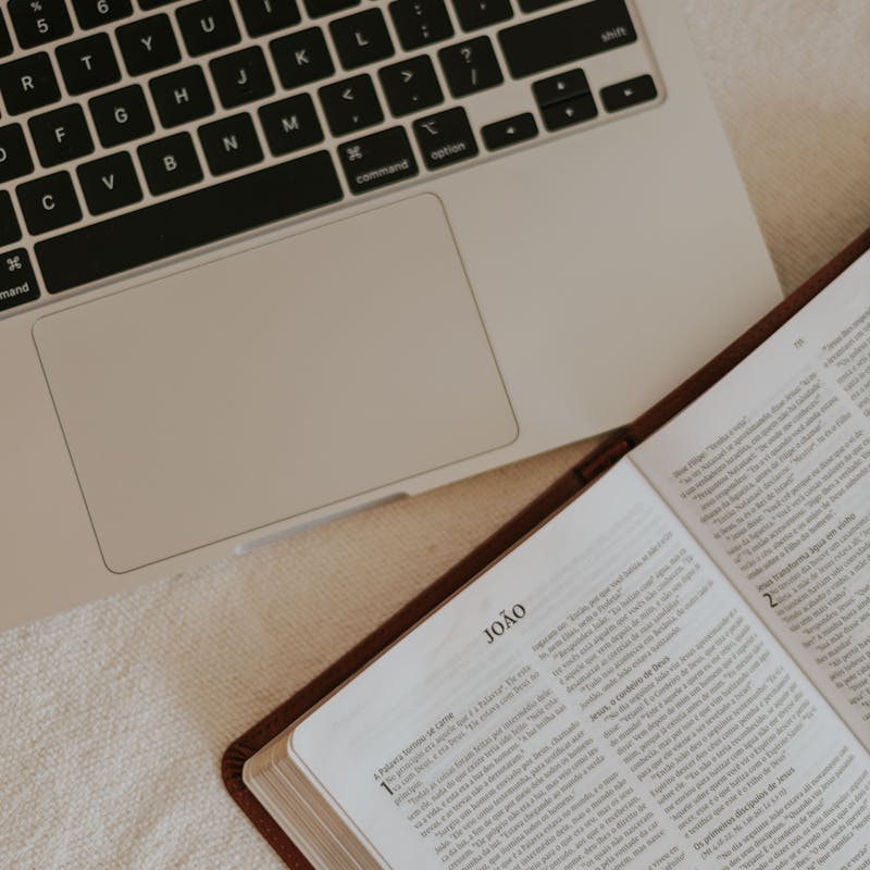 Bíblia aberta e laptop para estudo teológico online